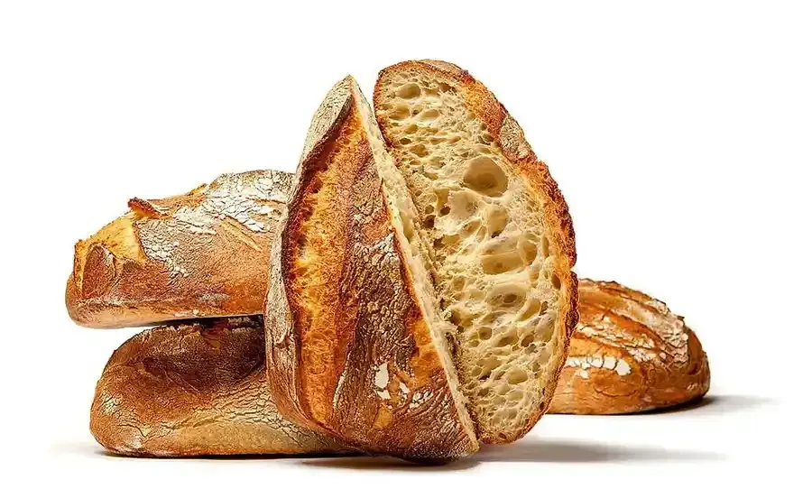 Three different types of bread are sitting on a wooden table.
