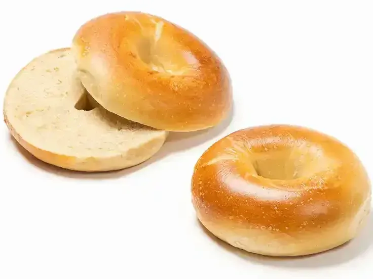 Two bagels with smoked salmon and cream cheese on a wooden table.