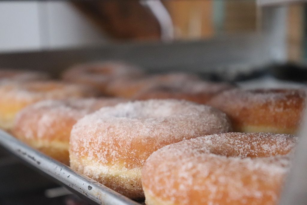 A tray of donuts with pink frosting and sprinkles