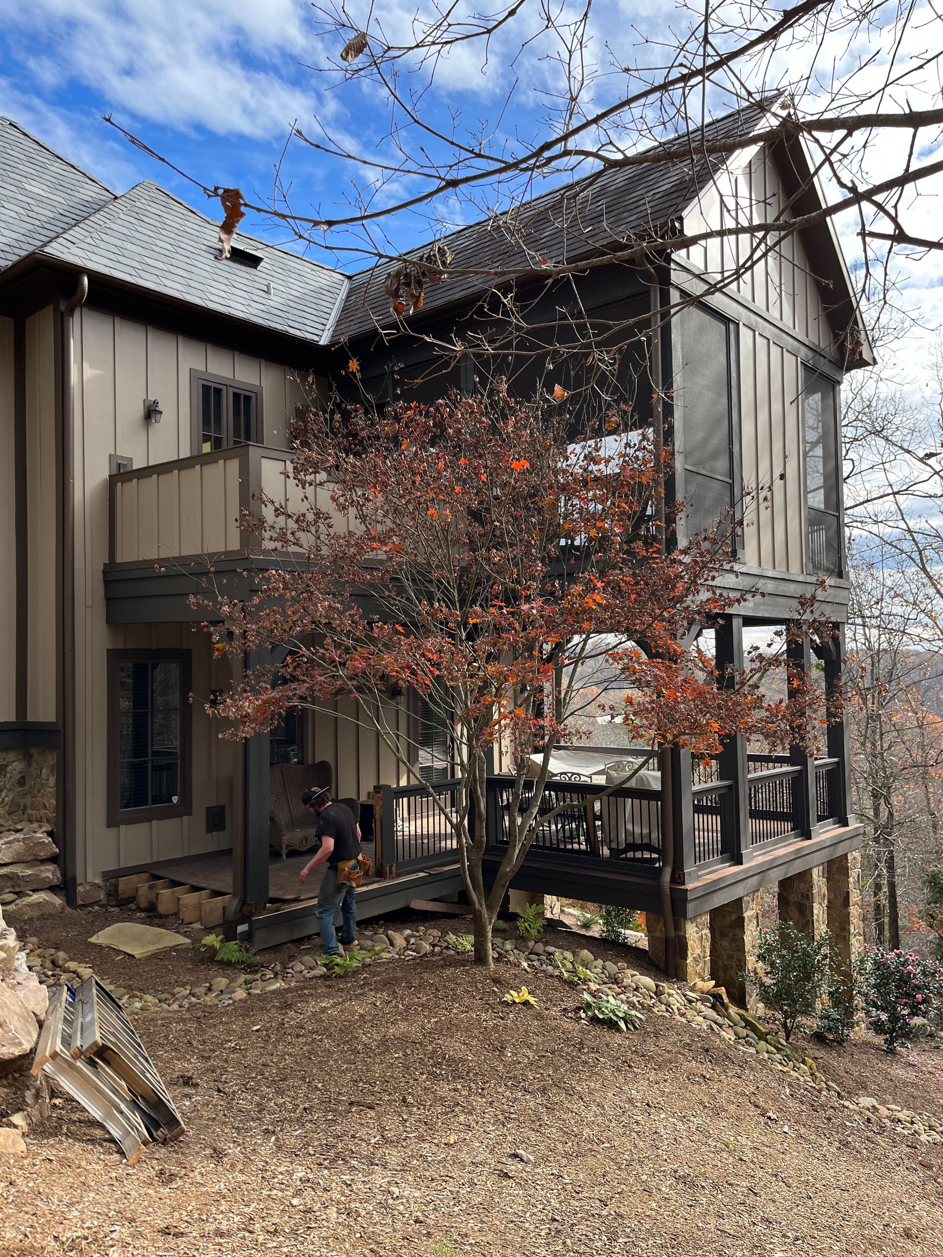 A man is standing in front of a house with a screened in porch.