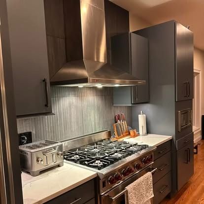 Modern kitchen with a gas range, stainless hood, gray cabinets, and white countertops