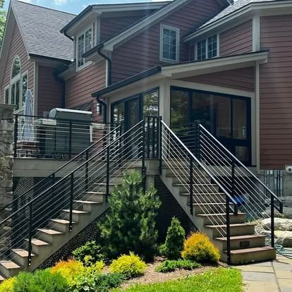Townhouse exterior with front stairs, black railings, and landscaped shrubs.