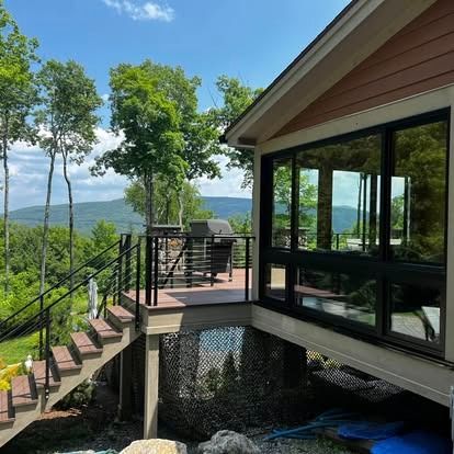 House deck and stairs overlooking a wooded mountain view on a sunny day