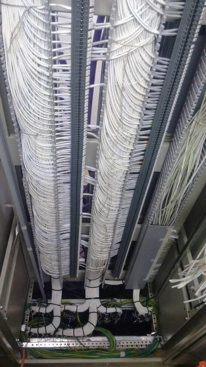 Bandejas portacables subterráneas con cables de red blancos y negros agrupados en el techo de una sala de servidores.