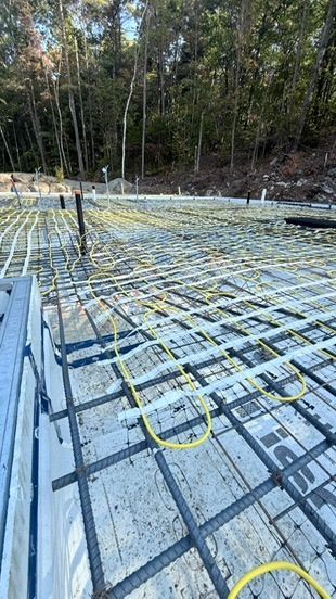Chantier équipé d'un système de chauffage au sol. Tuyaux jaunes sur fondations en béton armé.