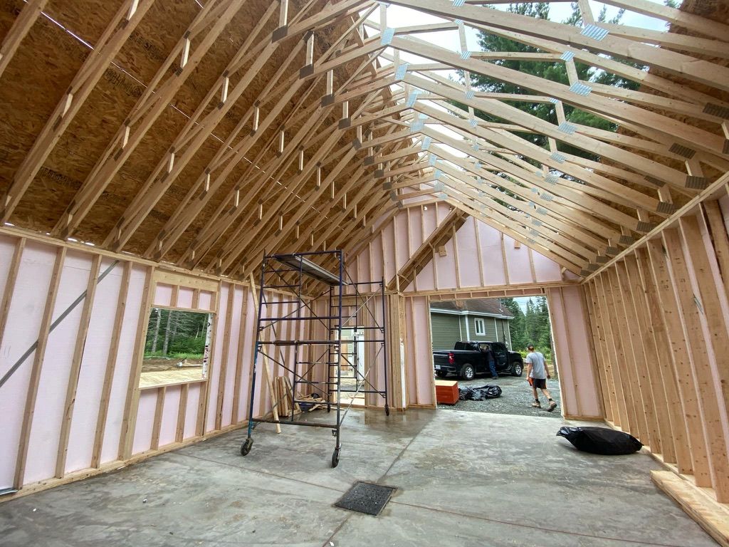 Intérieur d'un bâtiment à ossature bois en construction, comprenant les murs, le toit et les échafaudages.