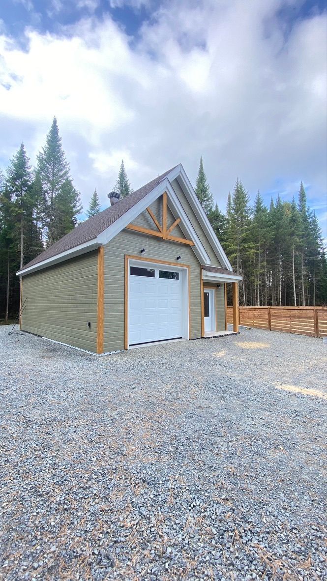 Garage avec porte blanche, touches de beige et allée en gravier.