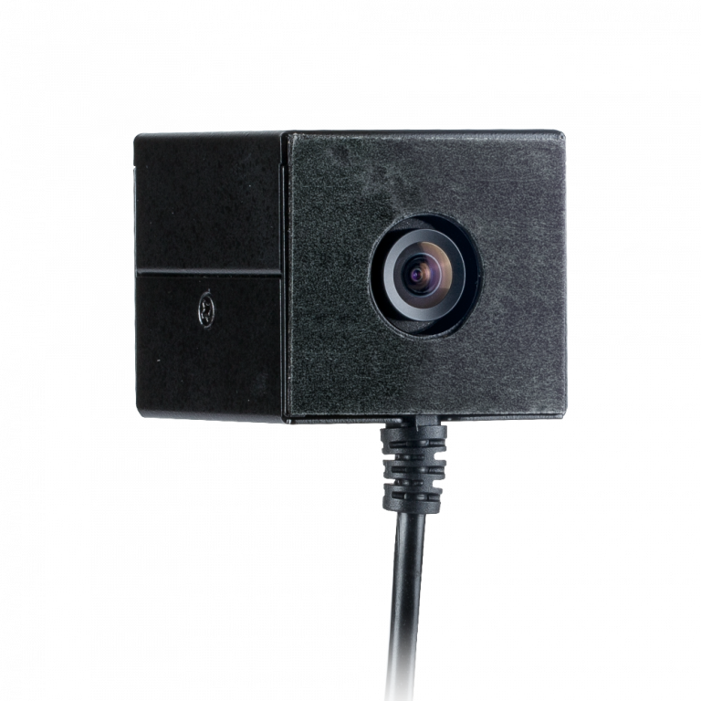 Black cube camera with a lens, attached to a cable, against a white background.