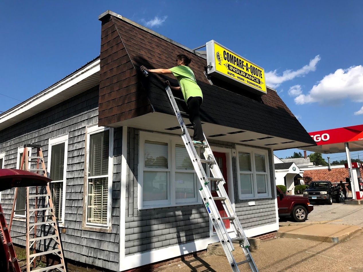 Person on a ladder cleaning a building's roof with a sign that says