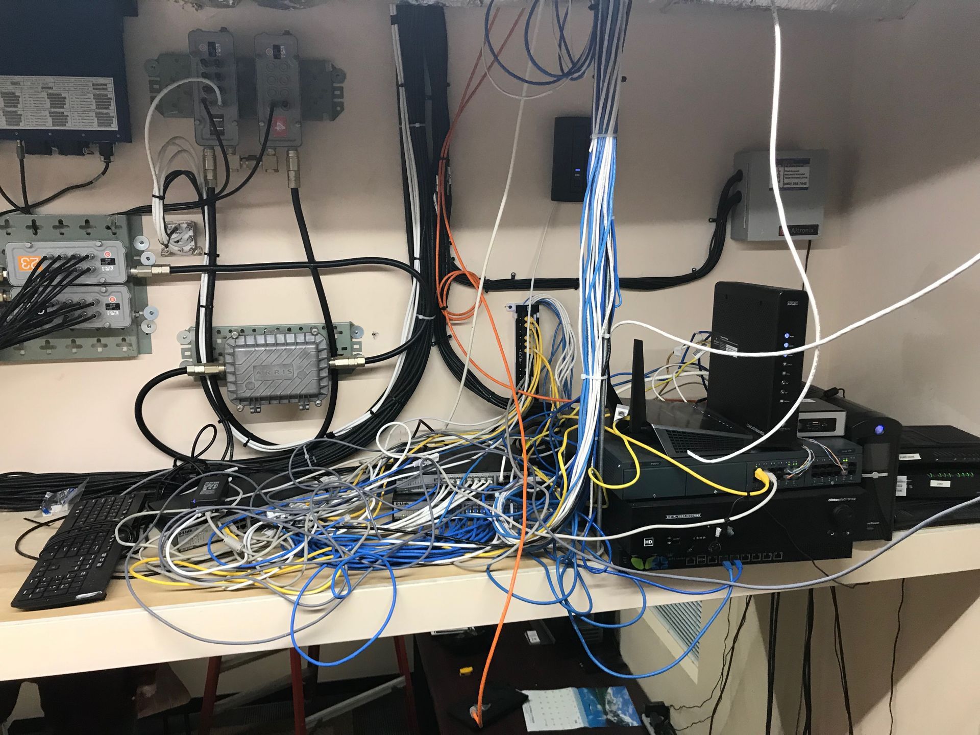 Tangled network cables and devices on a shelf, including routers, modems, and wall-mounted hardware.