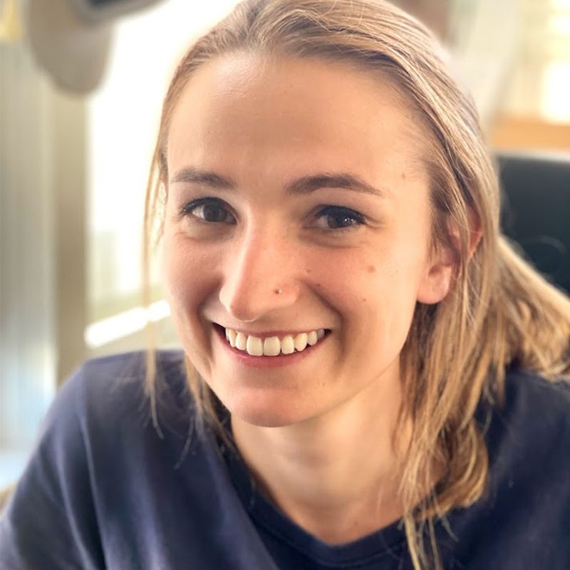 Woman with blonde hair smiling, wearing a blue shirt.