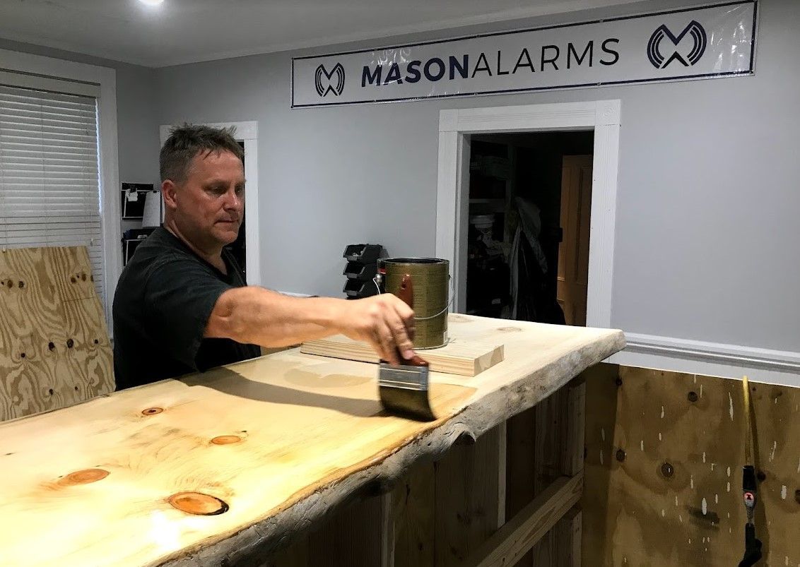 Man applying sealant to a wooden bar counter in a workshop,