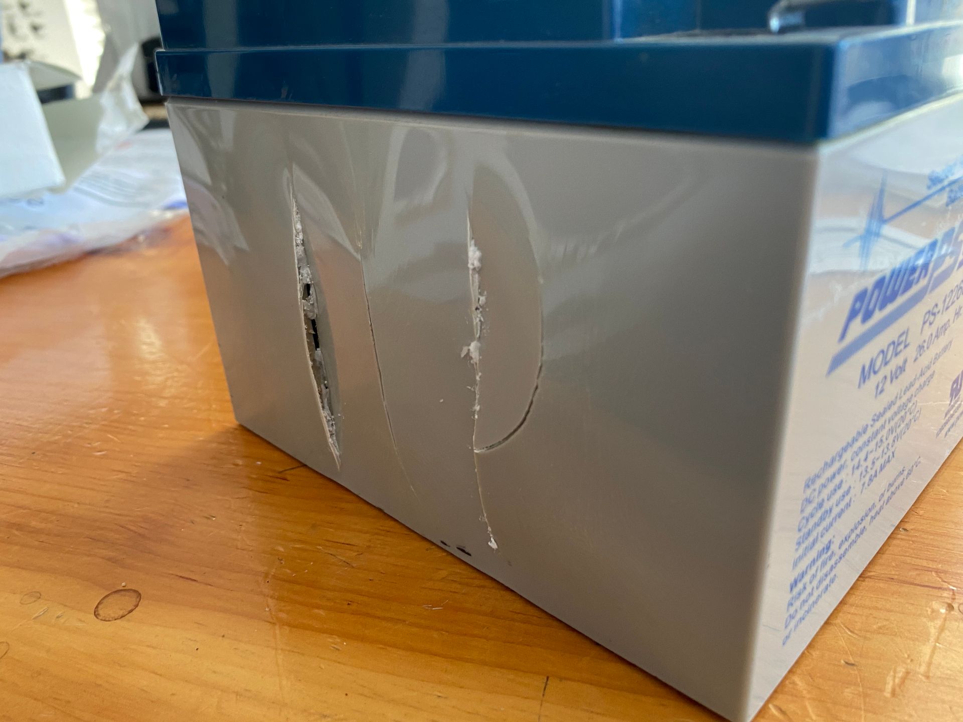 Damaged gray battery with blue top and deep gashes.