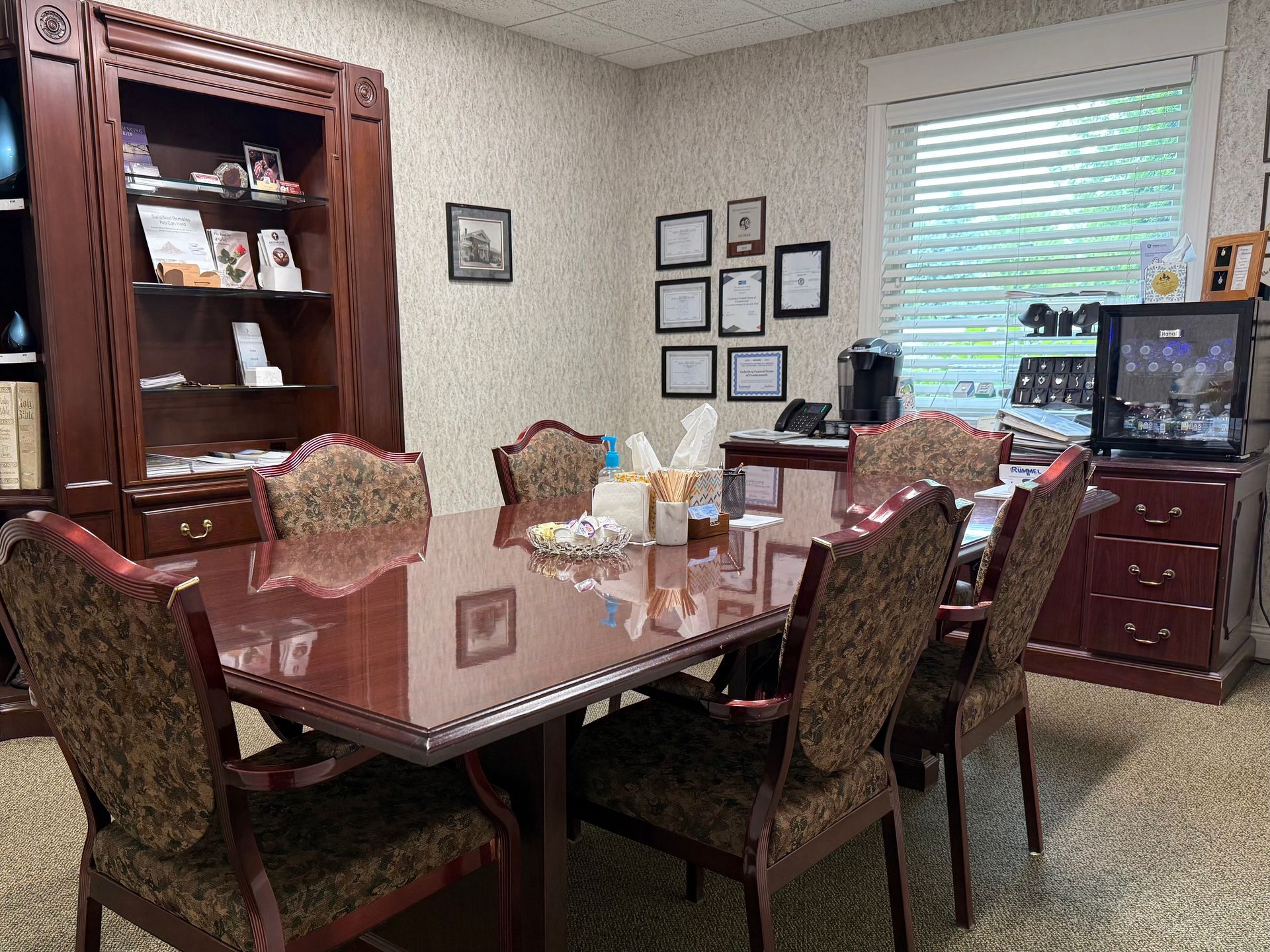 Dining room with a polished table, upholstered chairs, china cabinet, and window light.