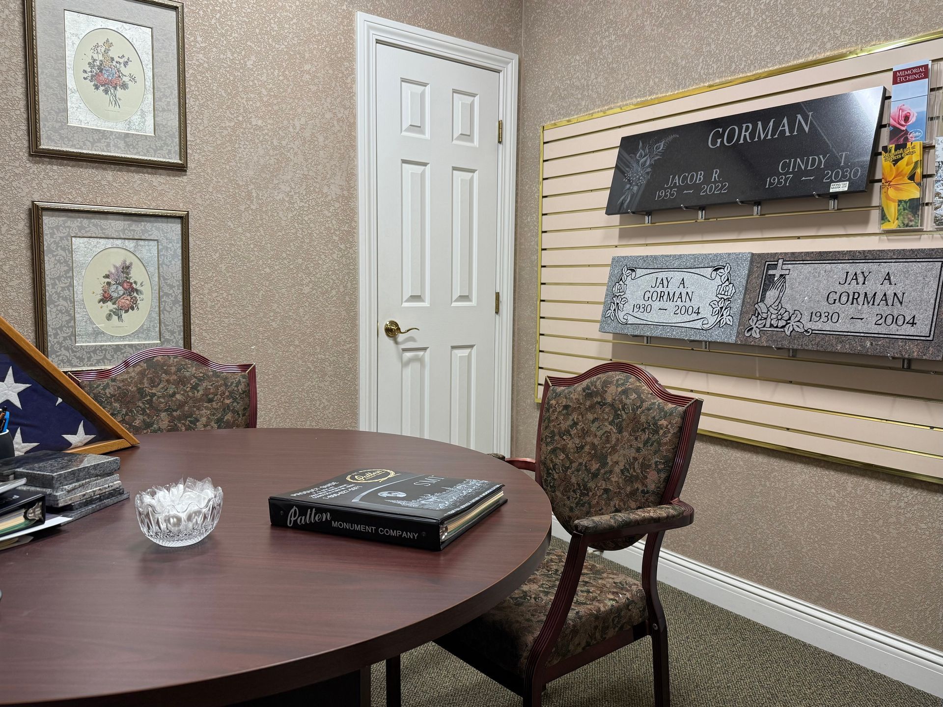 Conference room with round table, chairs, wall art, and mounted display screens.
