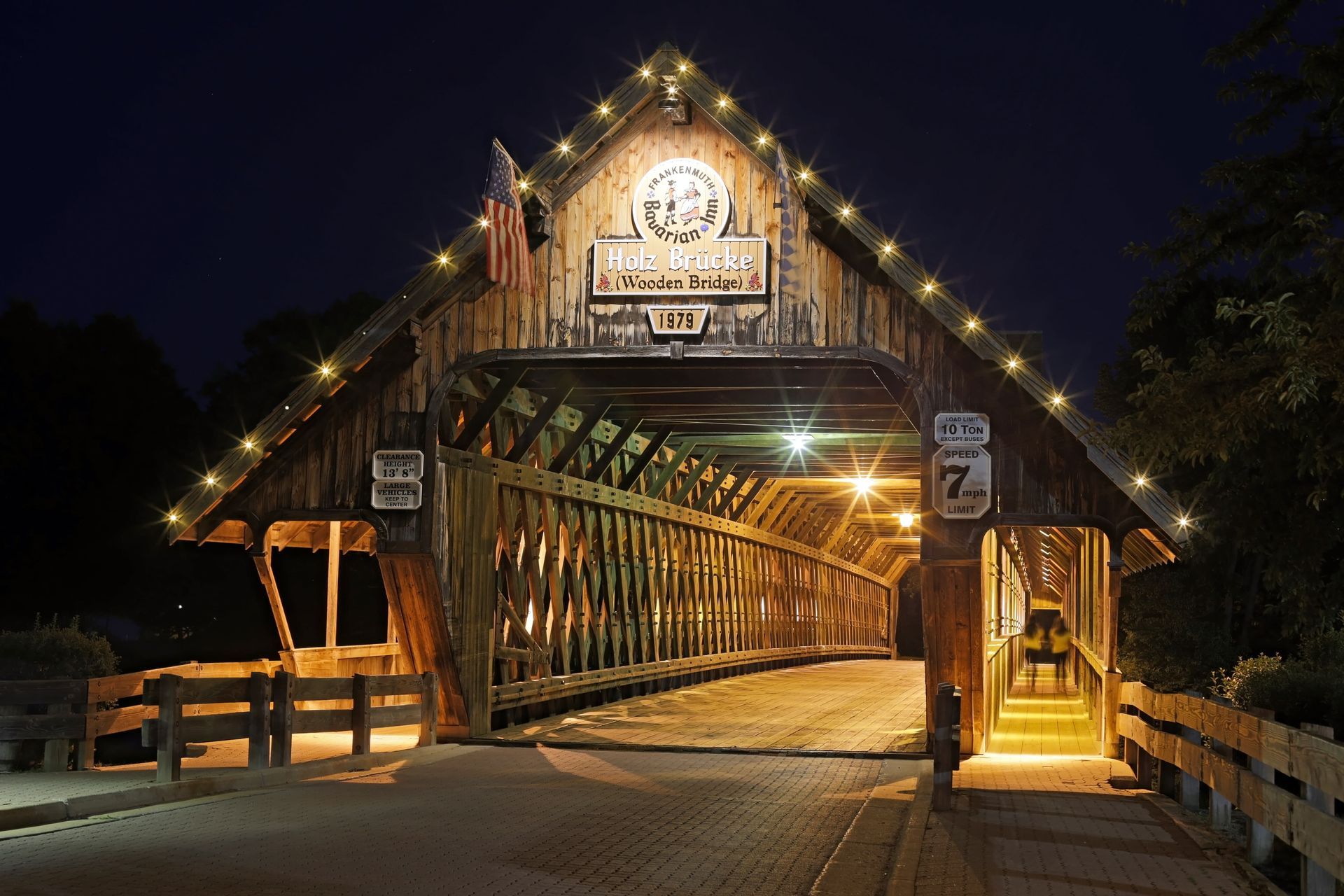 Illuminated wooden covered bridge at night with warm lights and a central walkway