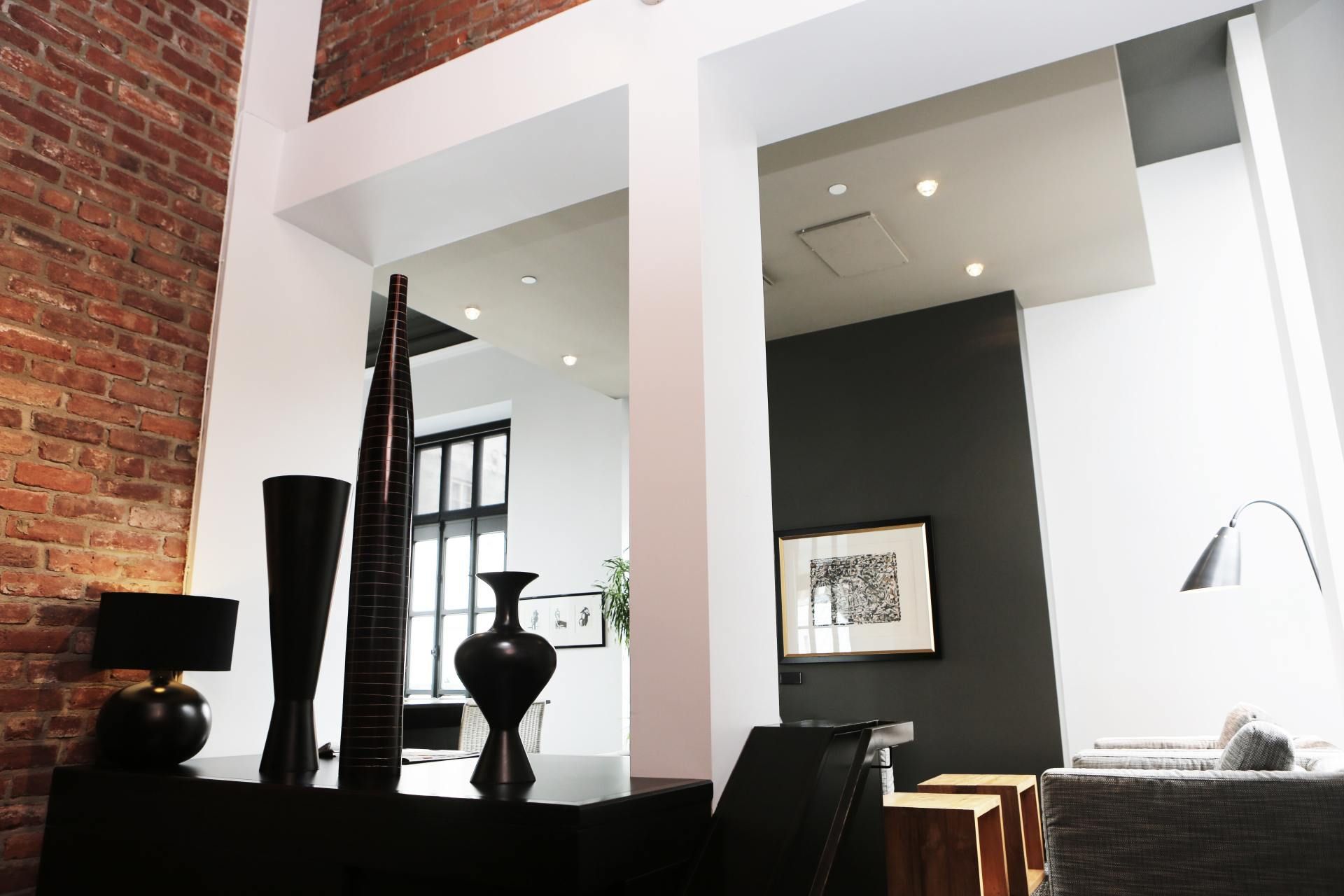 A living room with a brick wall and a table with vases on it
