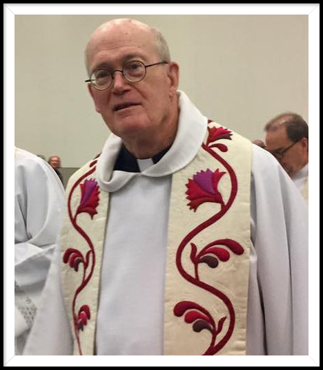 A priest wearing a white alb and a white liturgical stole decorated with red and purple floral embroidery.