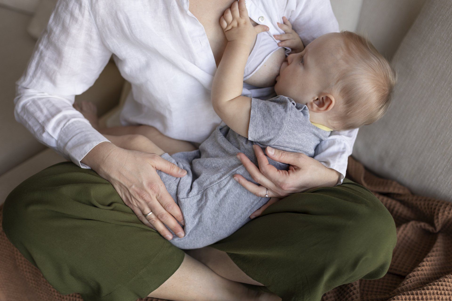 mulher vestindo camisa branca, amamentando bebê com roupa cinza