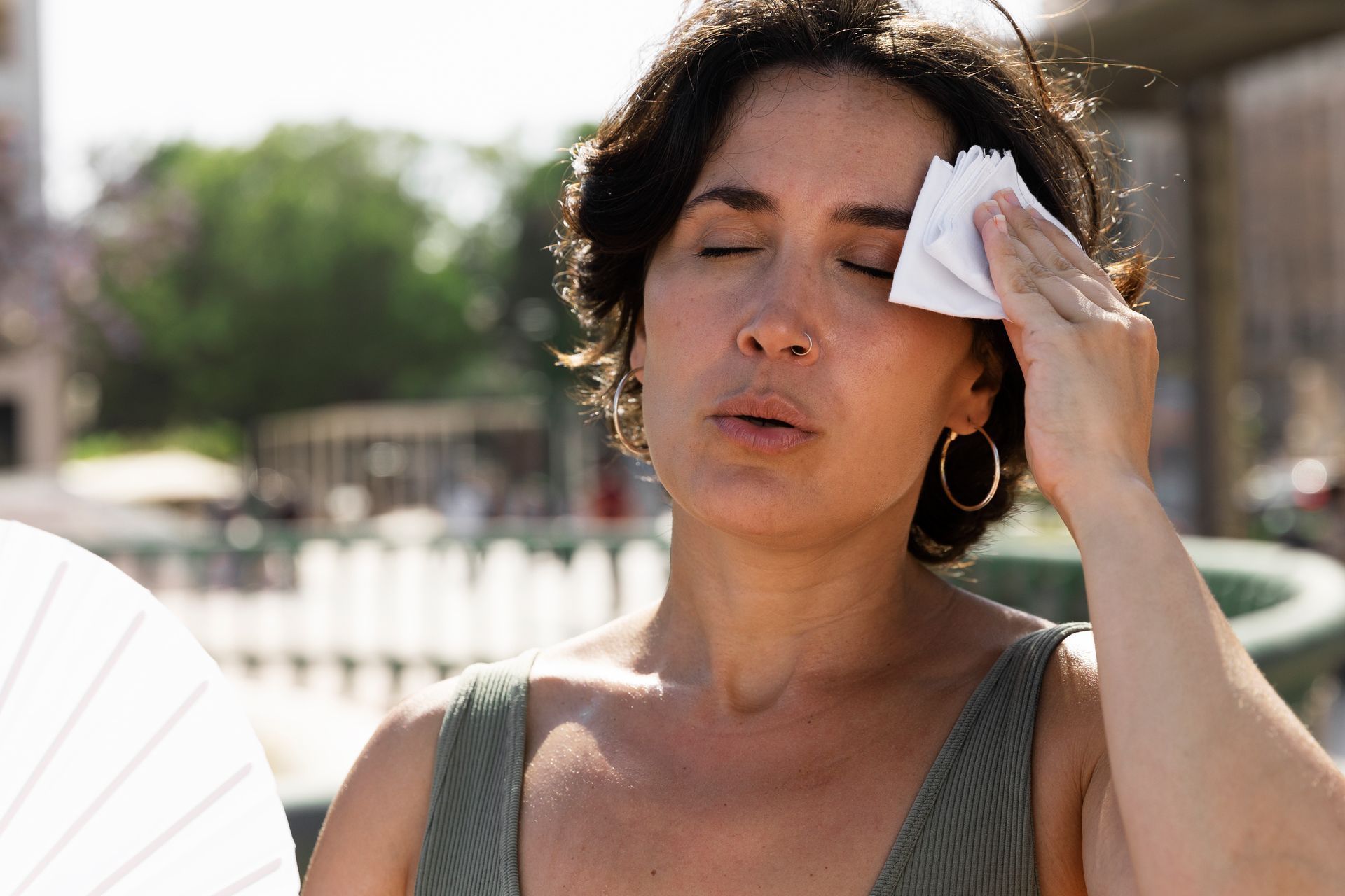 mulher com calor secando o suor com um lenço