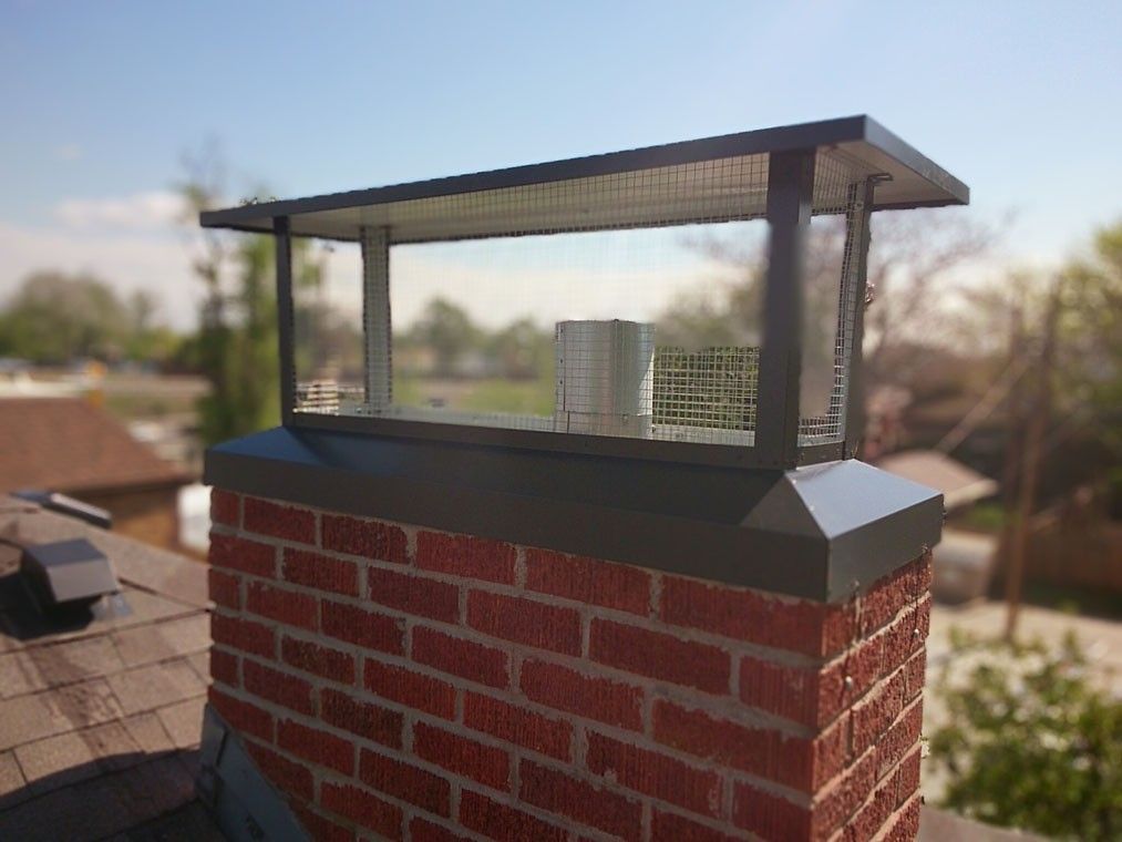 A brick chimney with a metal cap on top of it.