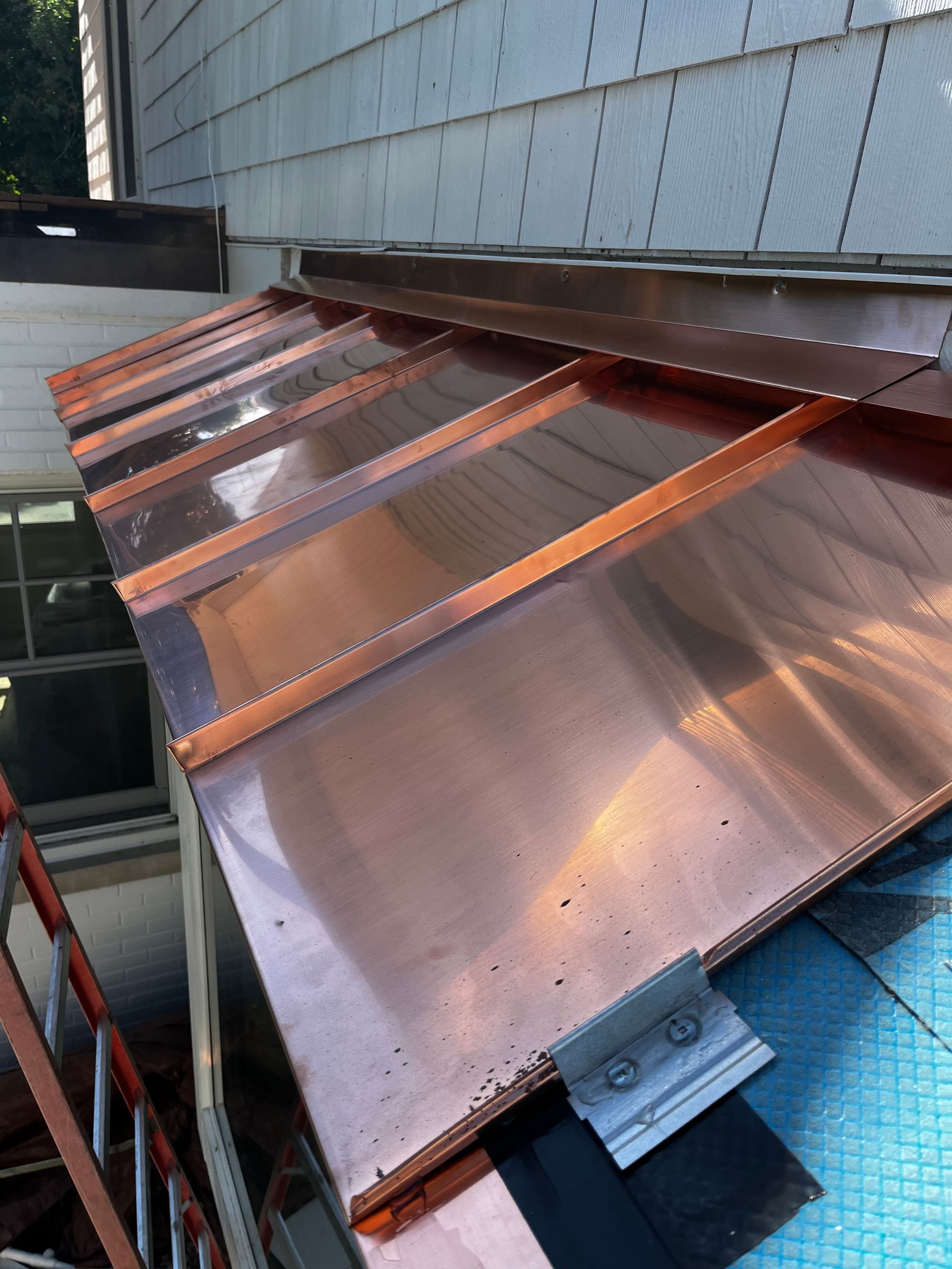 Custom standing seam copper roof installation with integrated copper wall flashing detail
