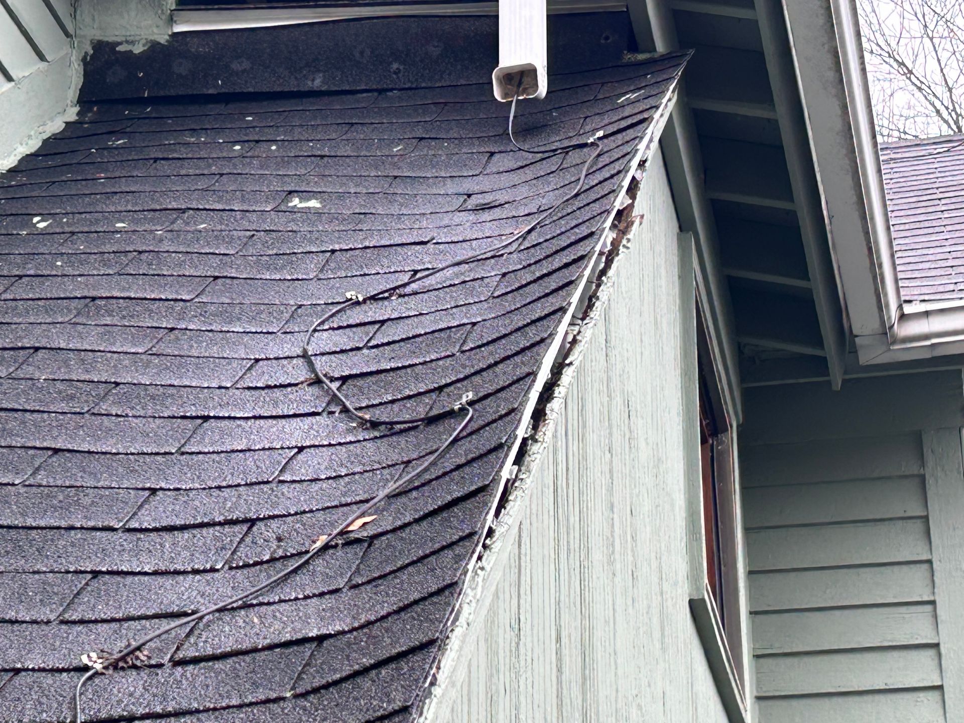 A close up of a roof with a gutter on the side of a house.