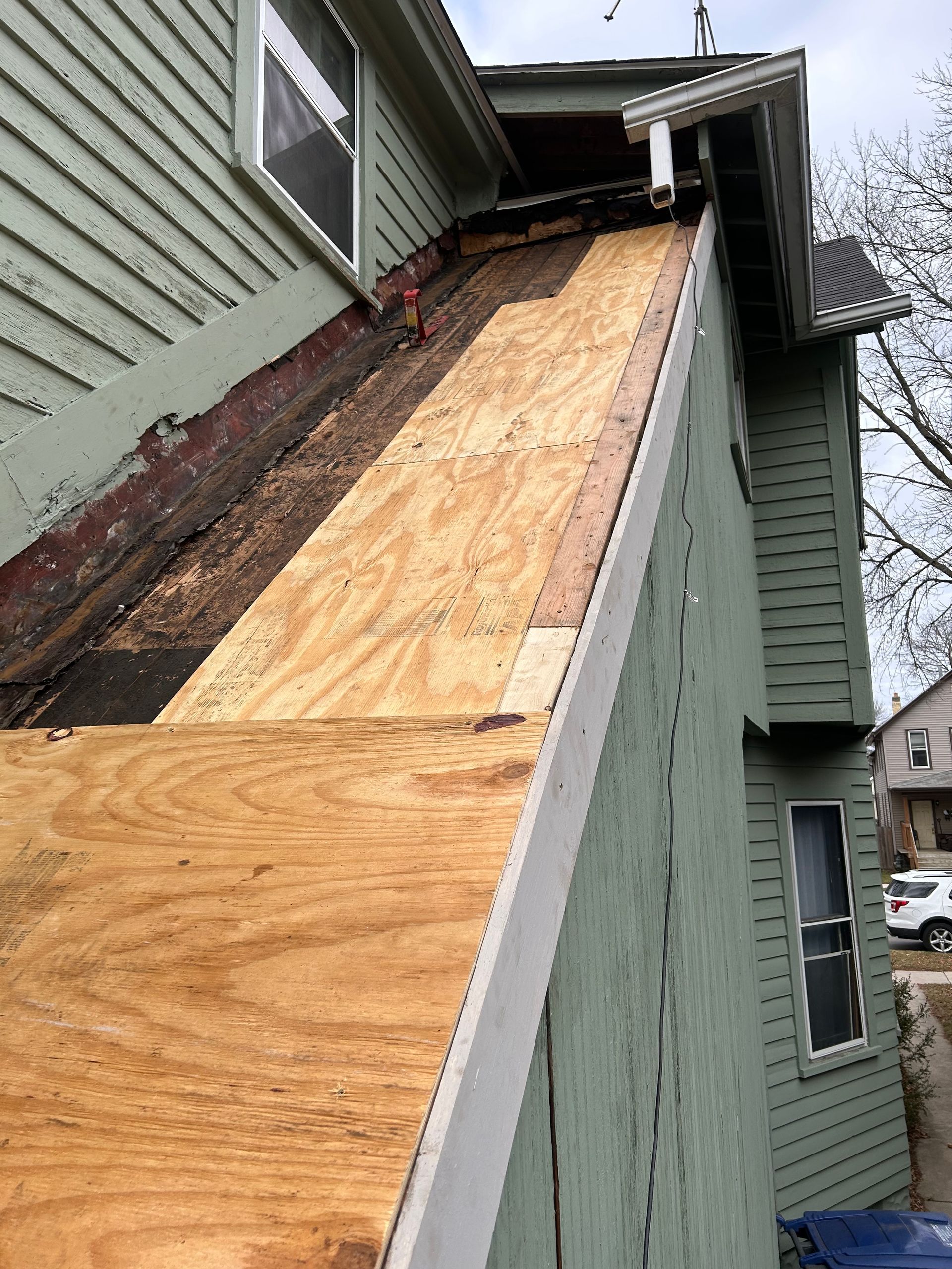 A house with a roof that is being repaired with plywood.