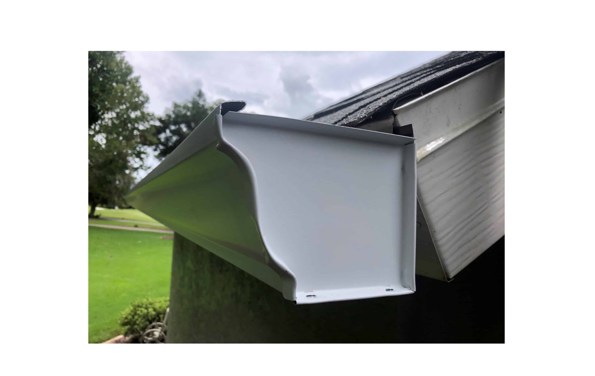 A white gutter is attached to the side of a house.