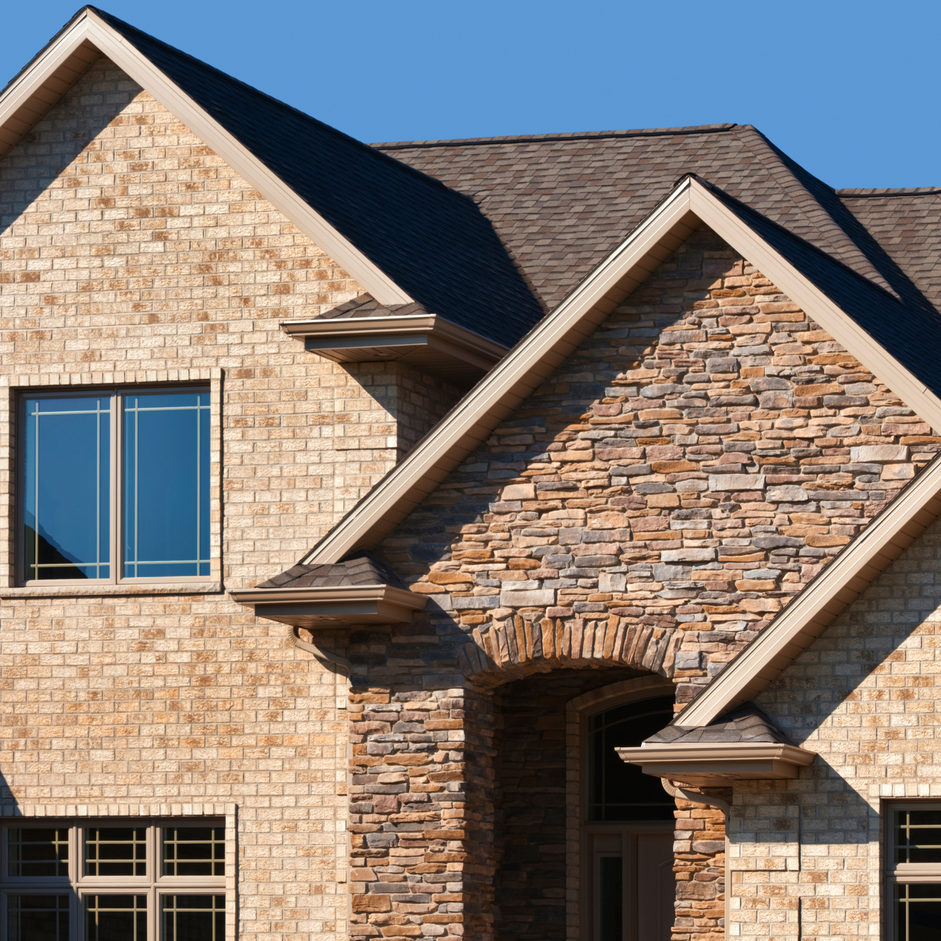 A brick house with a stone facade and a gray roof