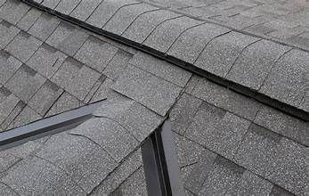 A close up of a roof with shingles and a metal railing.