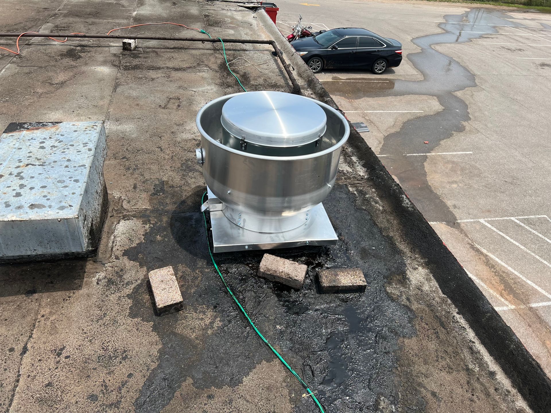 A stainless steel exhaust fan is on the roof of a building.