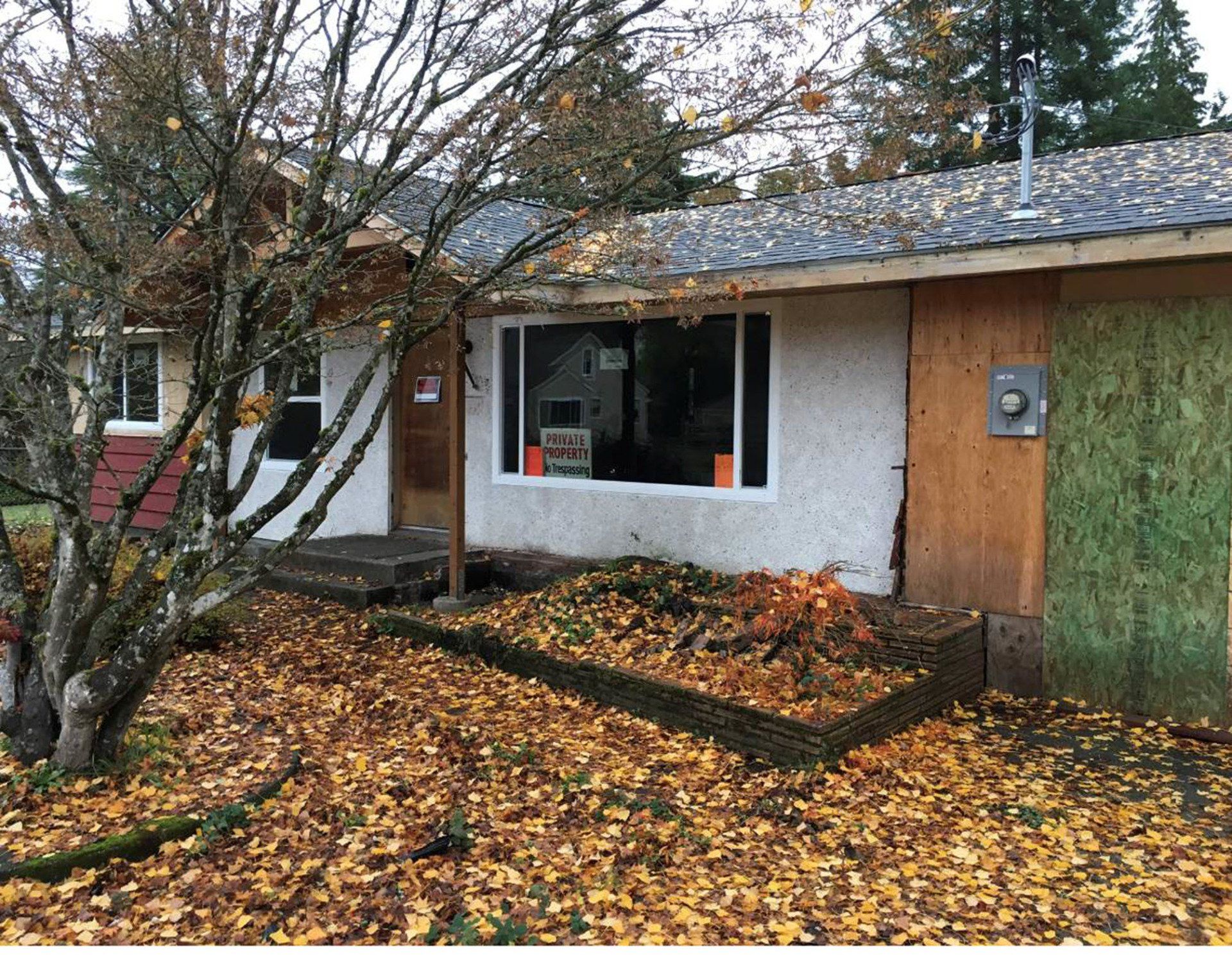Home exterior in need of renovation with boarded sections and aging siding, shown before remodel by ARDS Contracting in Seattle.