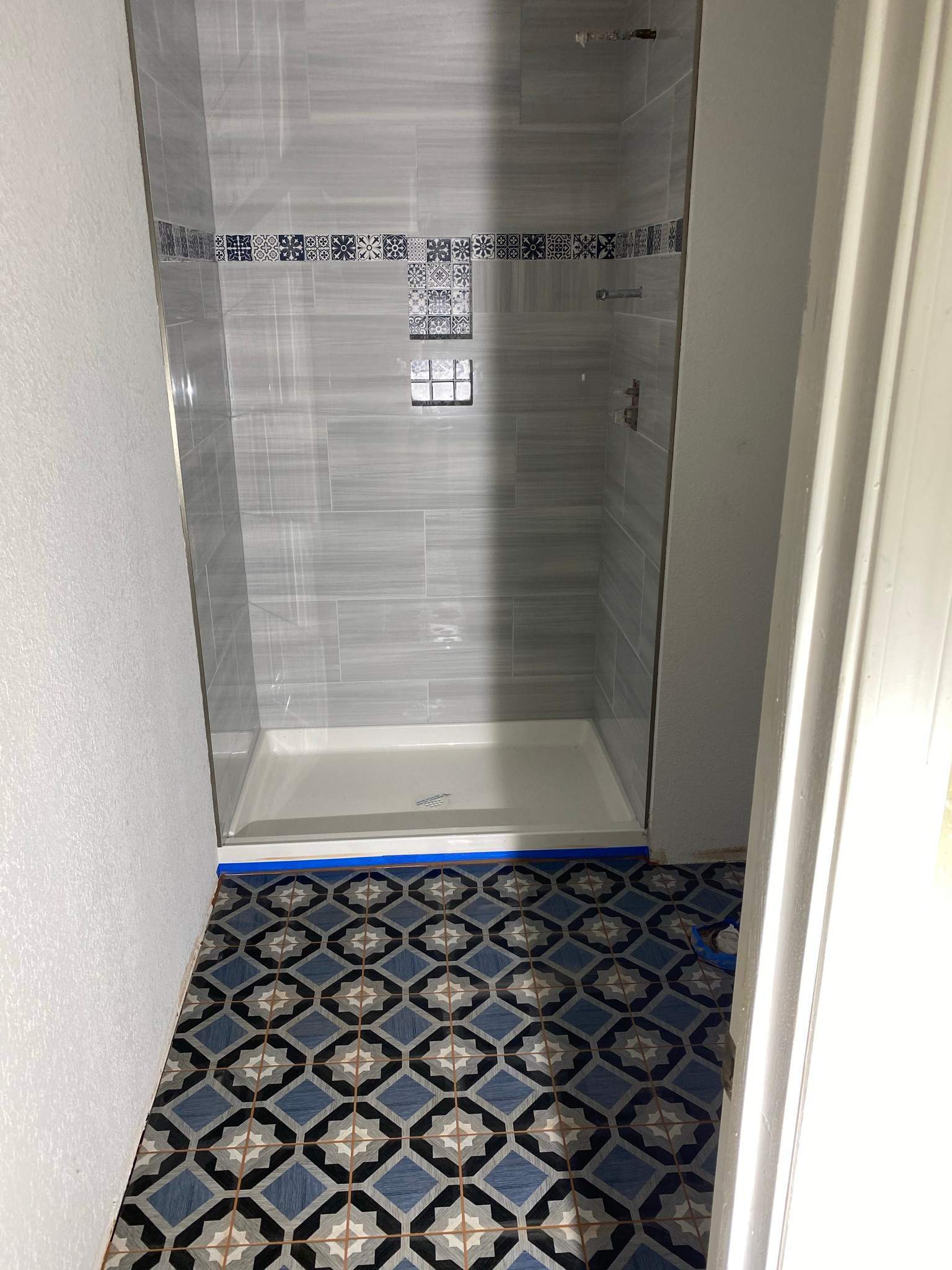 Bathroom remodel with modern gray tile shower and decorative accent strip installed by ARDS Contracting in Seattle.