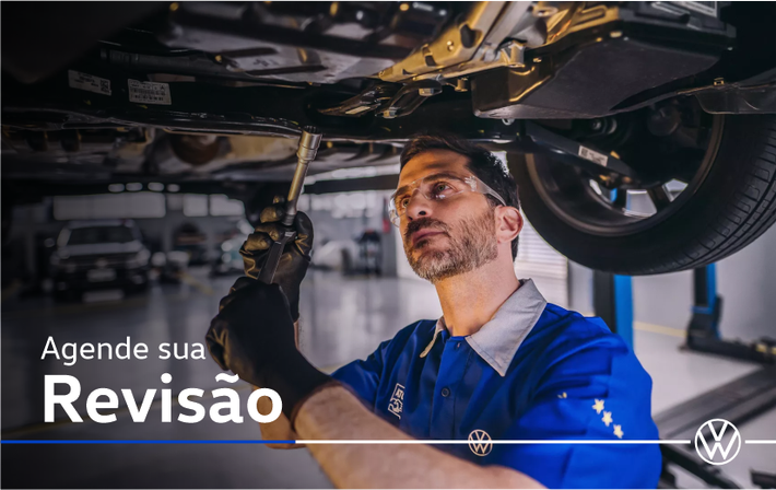 Um homem de camisa azul está trabalhando embaixo de um carro.