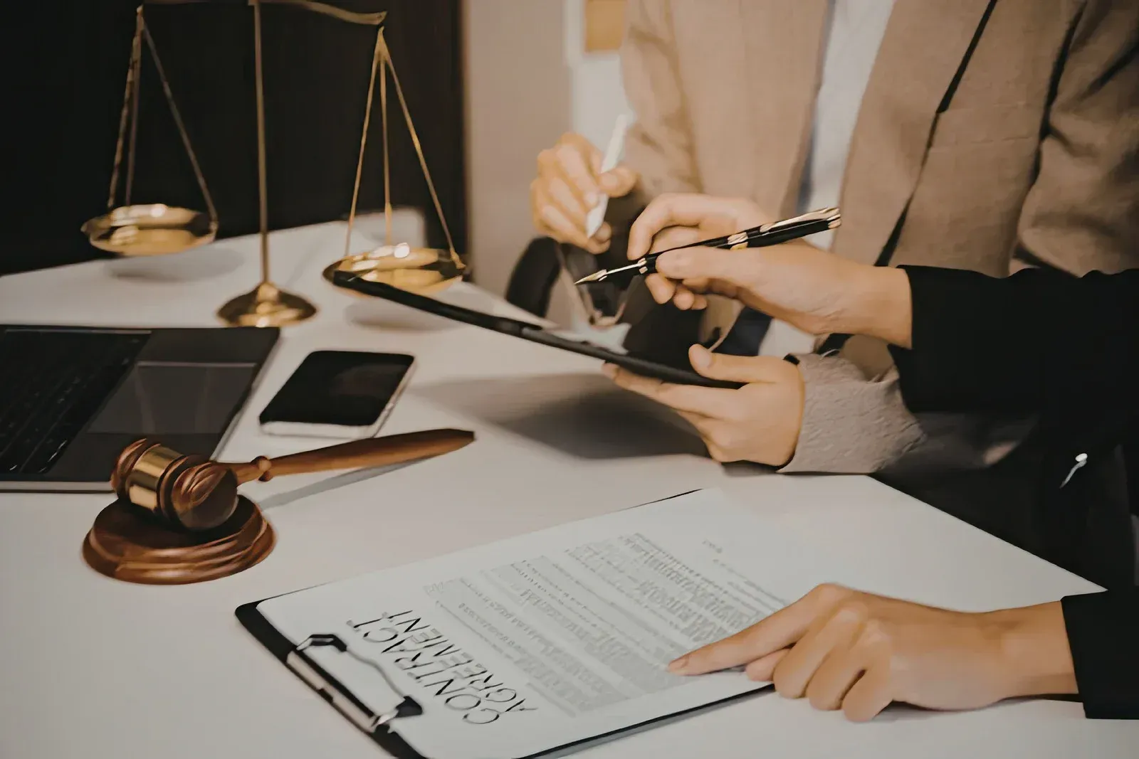 Legal professionals reviewing a contract at a desk with a gavel and scales of justice.