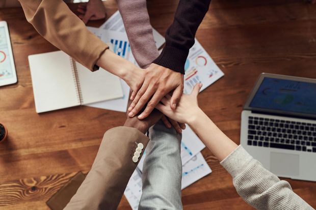 A group of business people are shaking hands over a table.