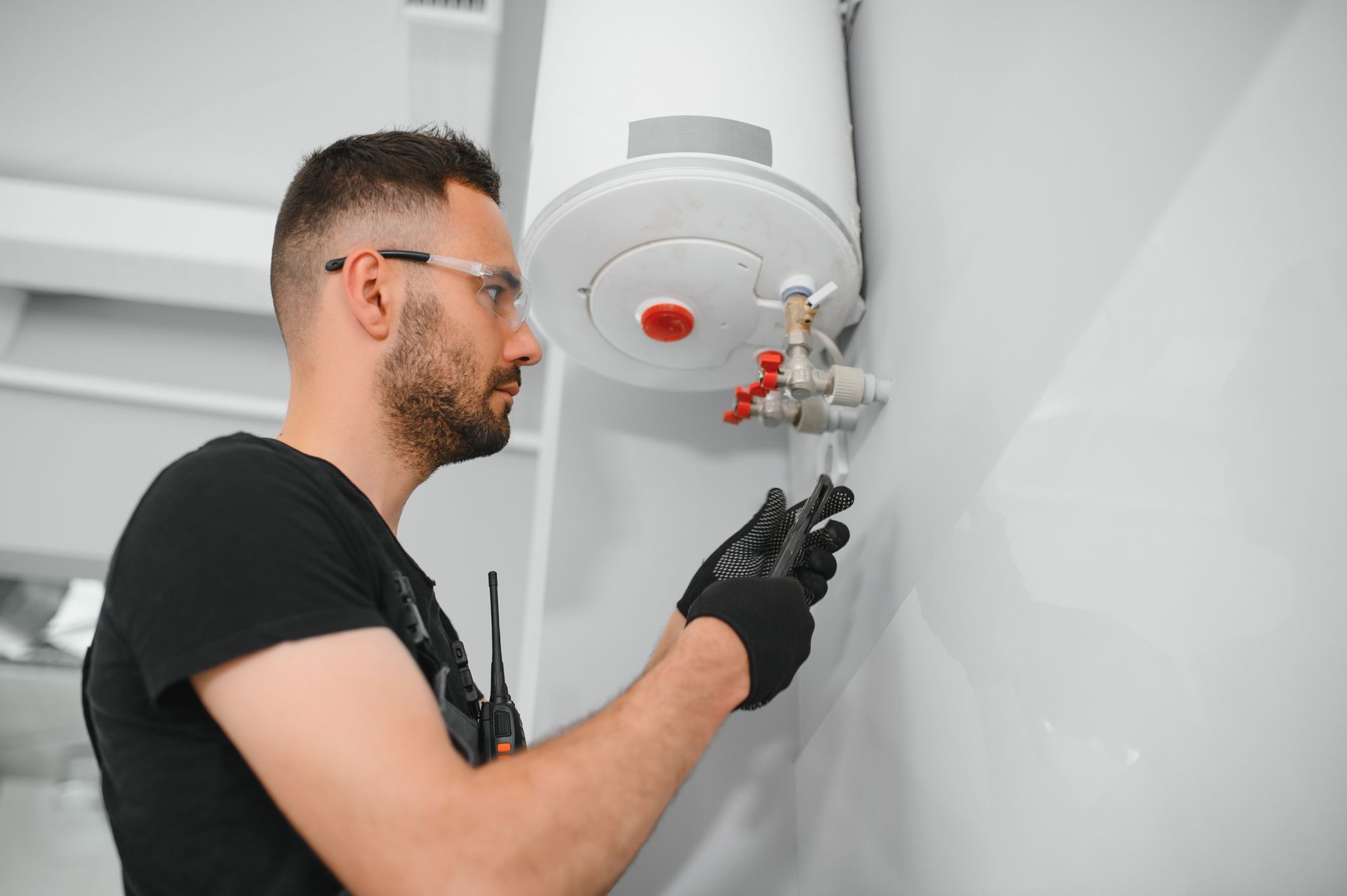 A man is fixing a water heater on the wall.