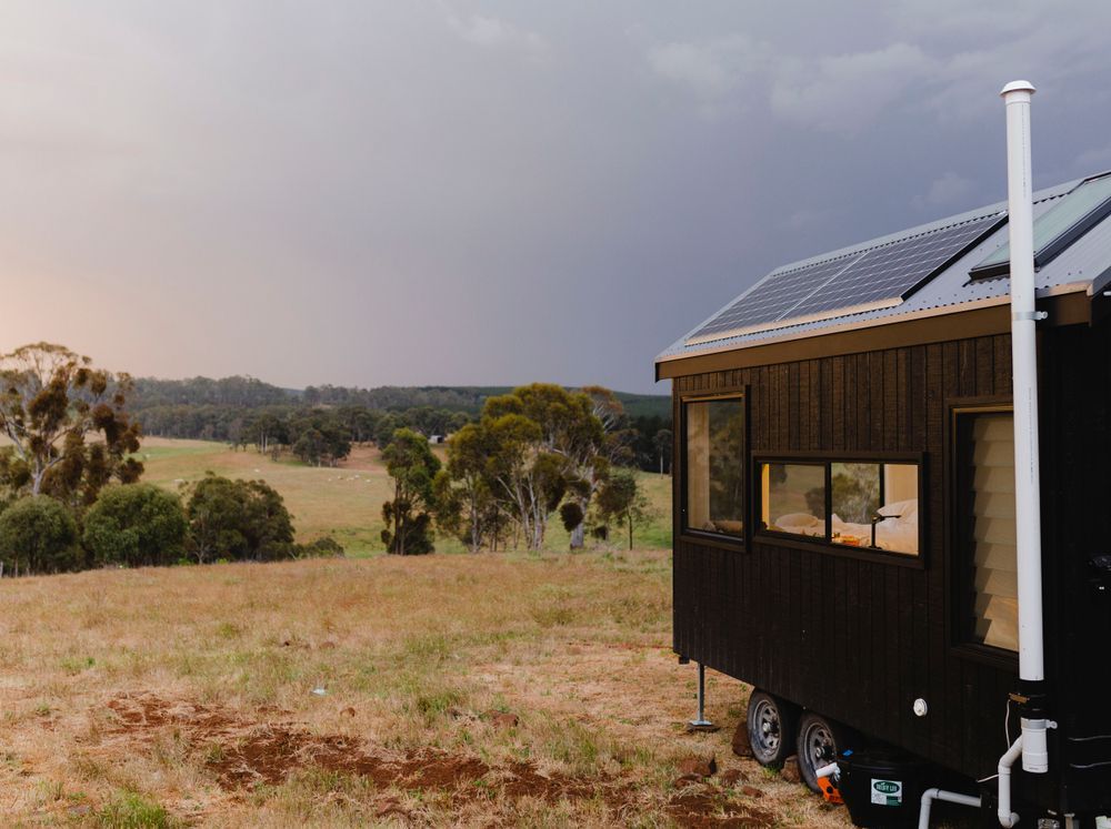 Black Tiny House on Wheels With Solar Panels, Overlooking a Grassy Field — Kellie O'Malley Conveyancing In Singleton, NSW