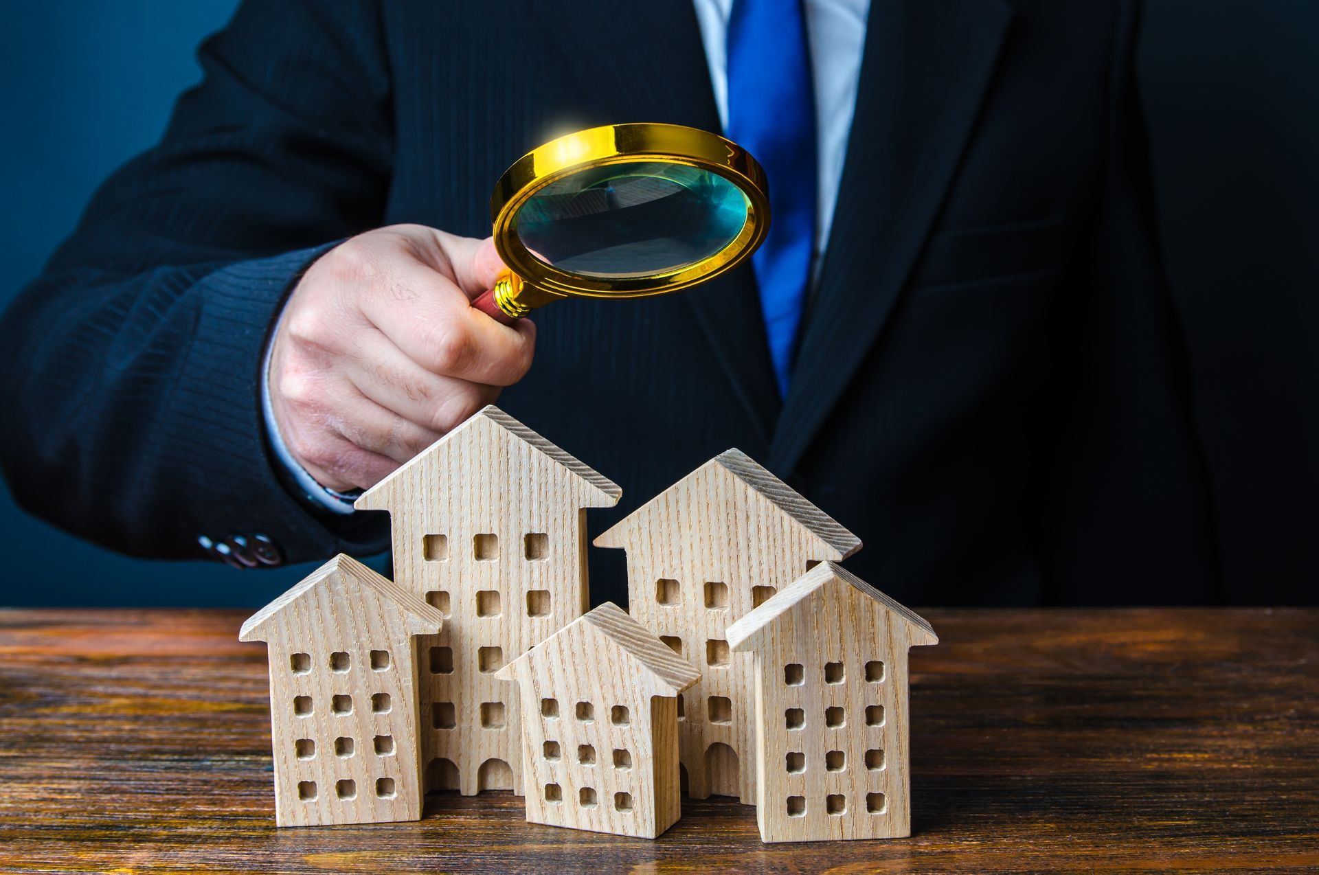 Person in Suit Examines Miniature Houses With a Magnifying Glass — Kellie O'Malley Conveyancing In Lake Munmorah, NSW