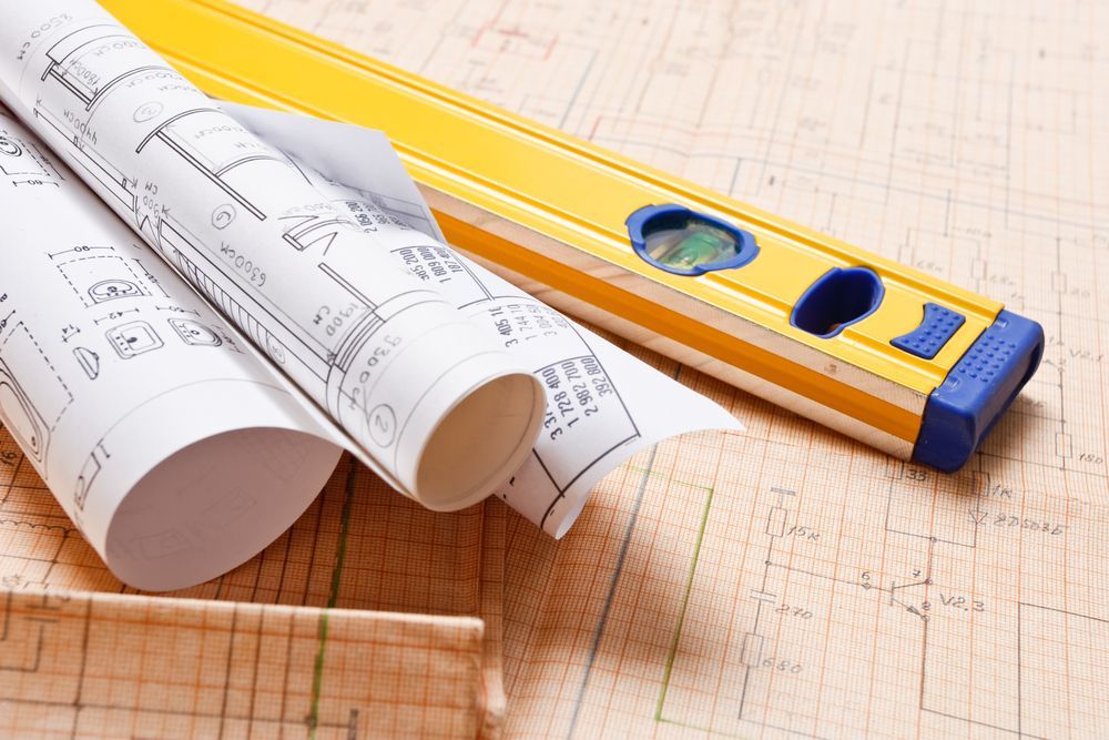 Rolled Blueprints and Yellow Level Resting on a Topographic Map — Kellie O'Malley Conveyancing In Lake Munmorah, NSW