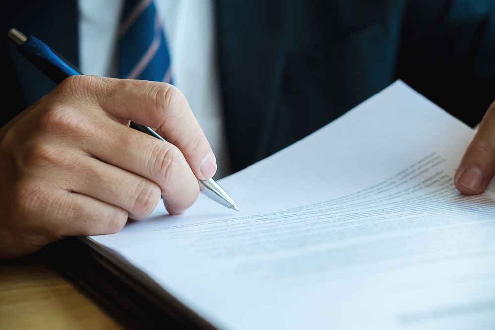 Person's Hand Writing With a Pen on White Paper — Kellie O'Malley Conveyancing In Lake Munmorah, NSW