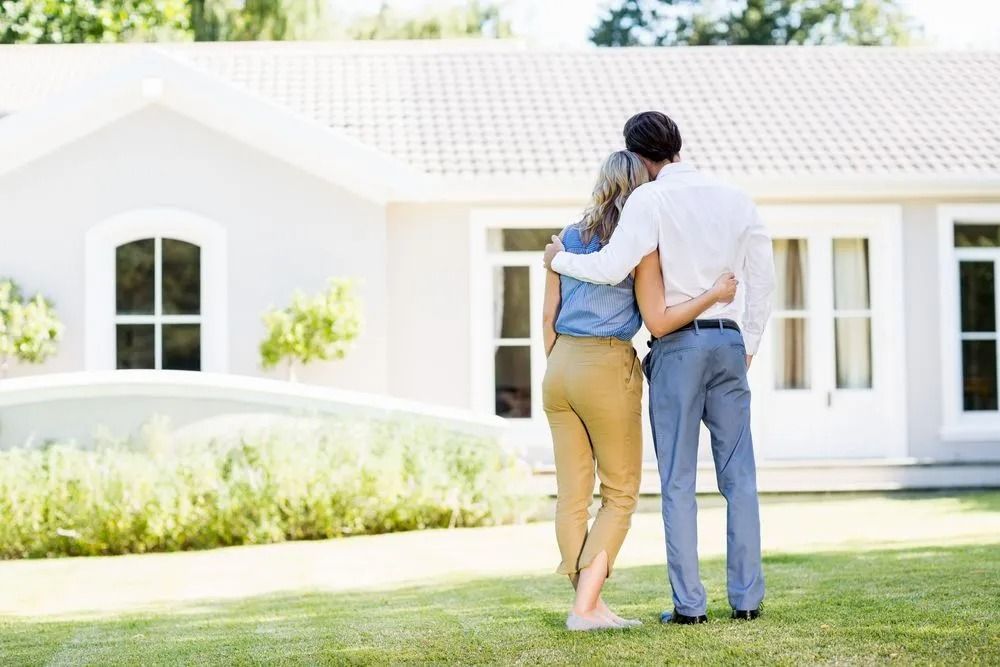 Couple With Arms Around Each Other Looking at a Light-coloured House — Kellie O'Malley Conveyancing In Liverpool Plains, NSW