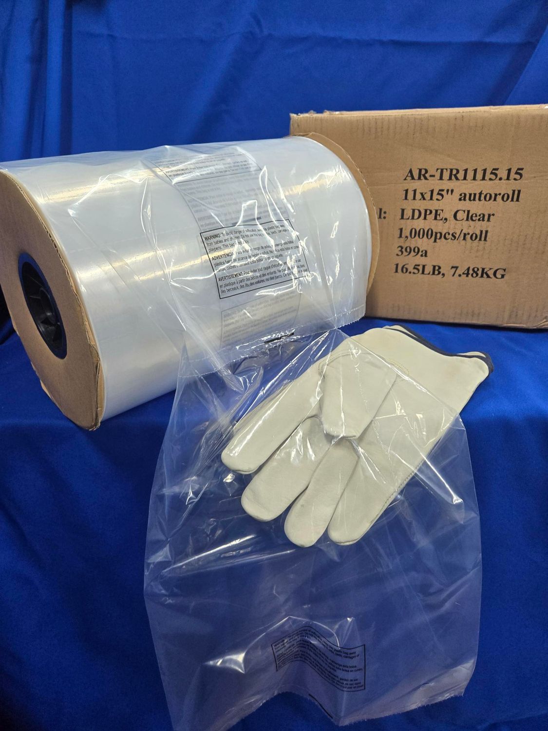 Roll of clear plastic tubing, open plastic bag, work gloves, and cardboard box against a blue backdrop.