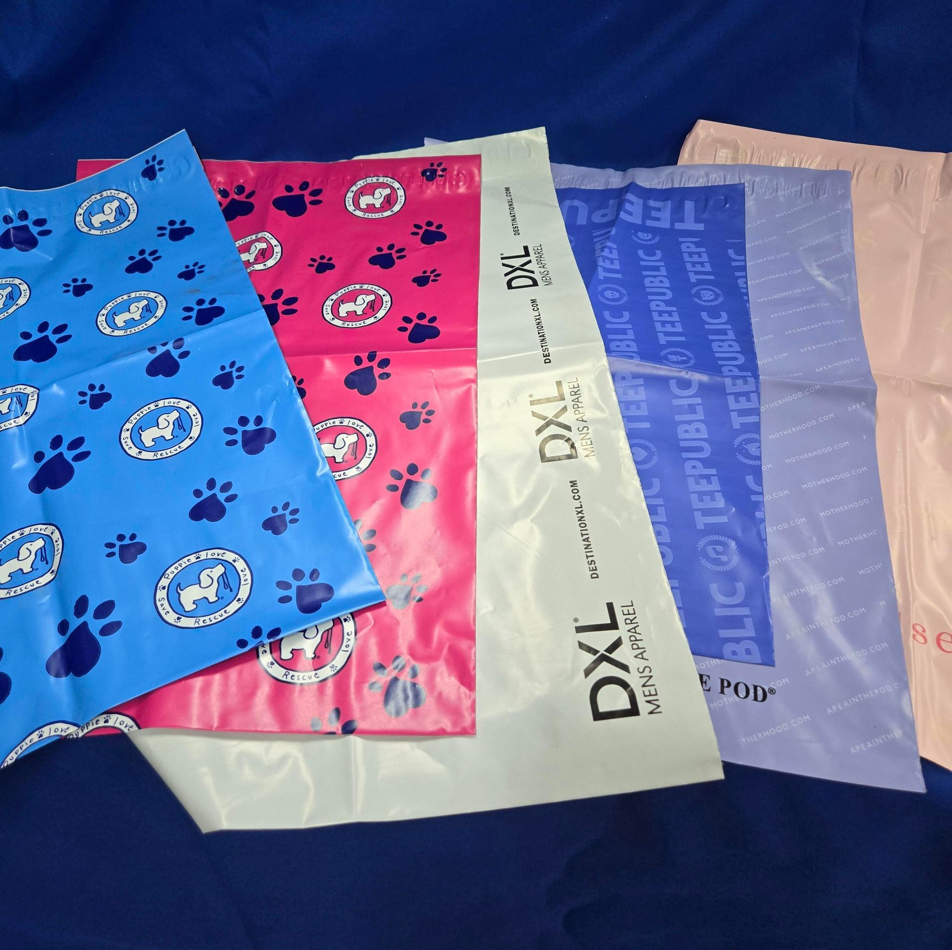 Various colorful plastic bags, some with paw prints and logos, on a blue surface.