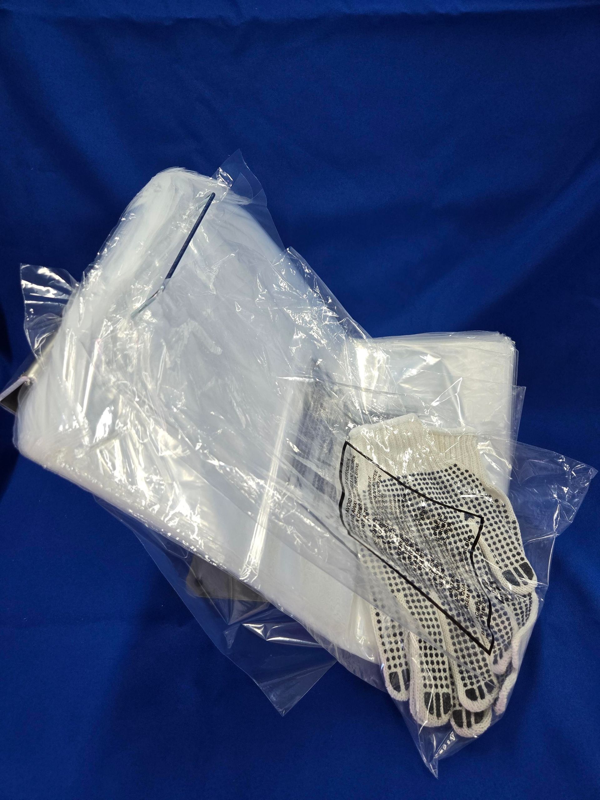 Clear plastic bags and a pair of patterned gloves on a blue surface.