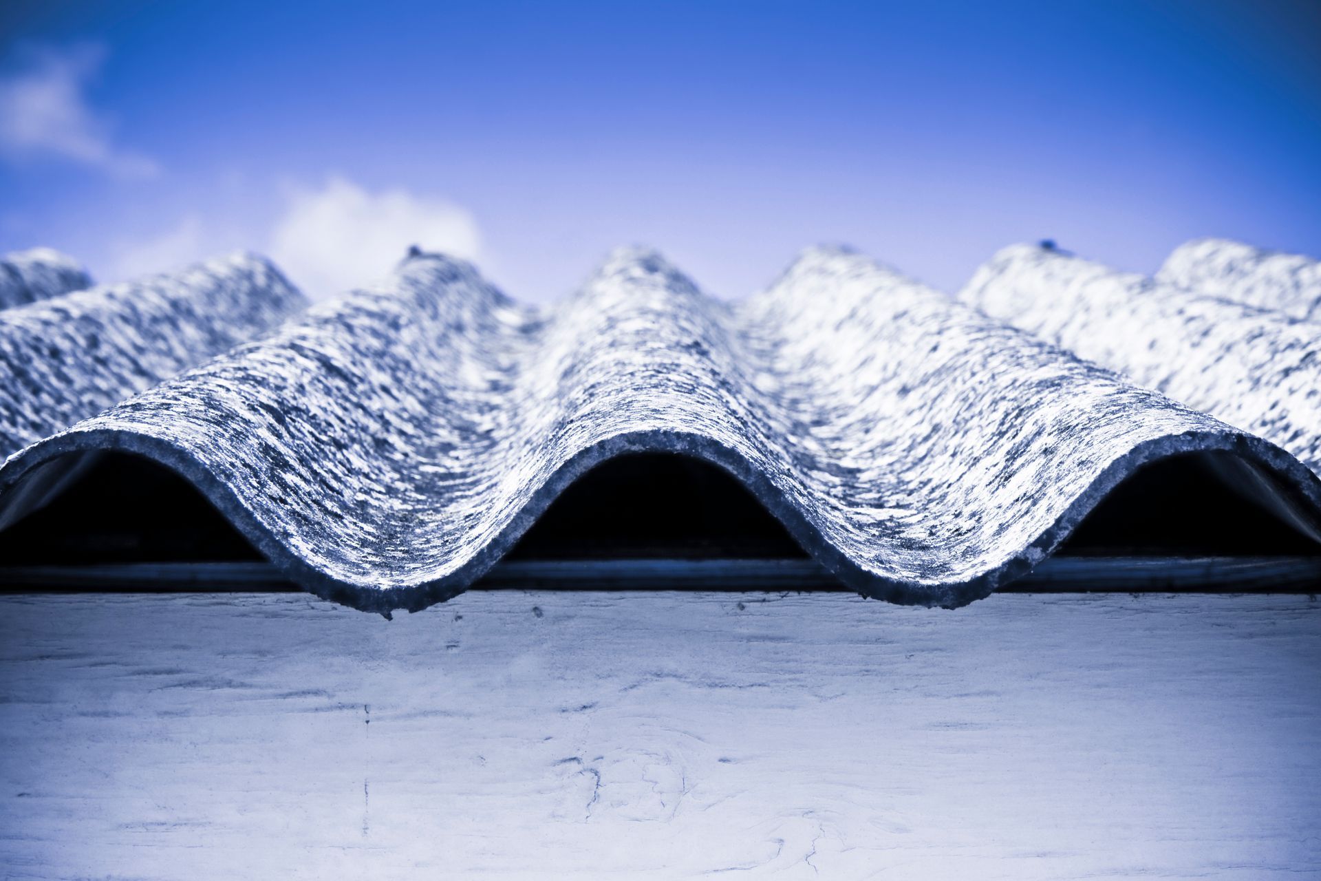 Close-up of a textured roof against a clear blue sky, highlighting asbetos.