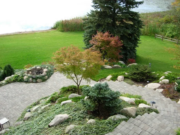 Landscaped garden with gravel paths, shrubs, rocks, and a green lawn