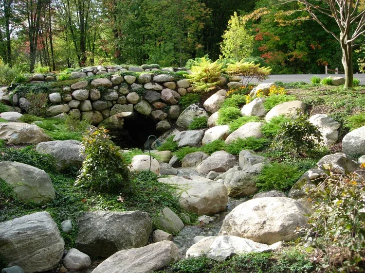 Stone garden with a rock stream bed, mossy boulders, and green trees in the background
