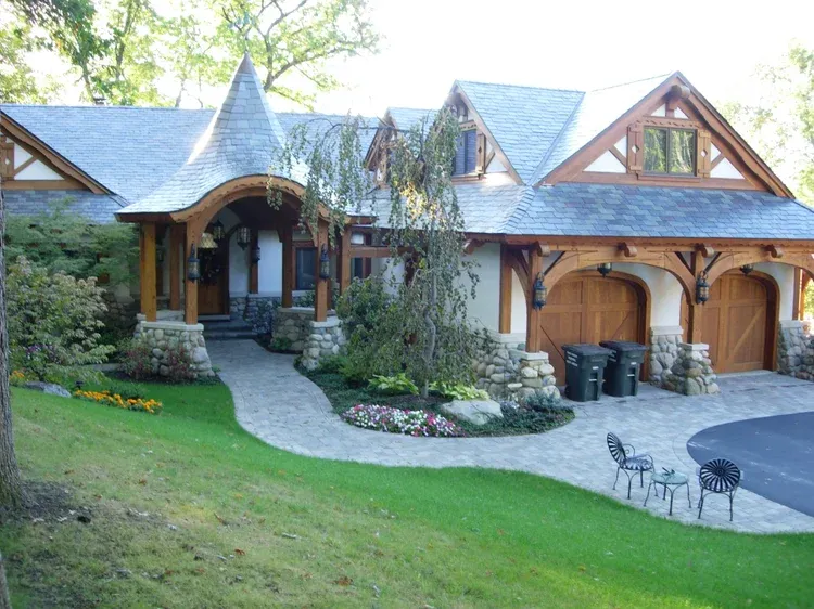 Large rustic house with wood siding, stone walkway, arched garage, and green lawn in front